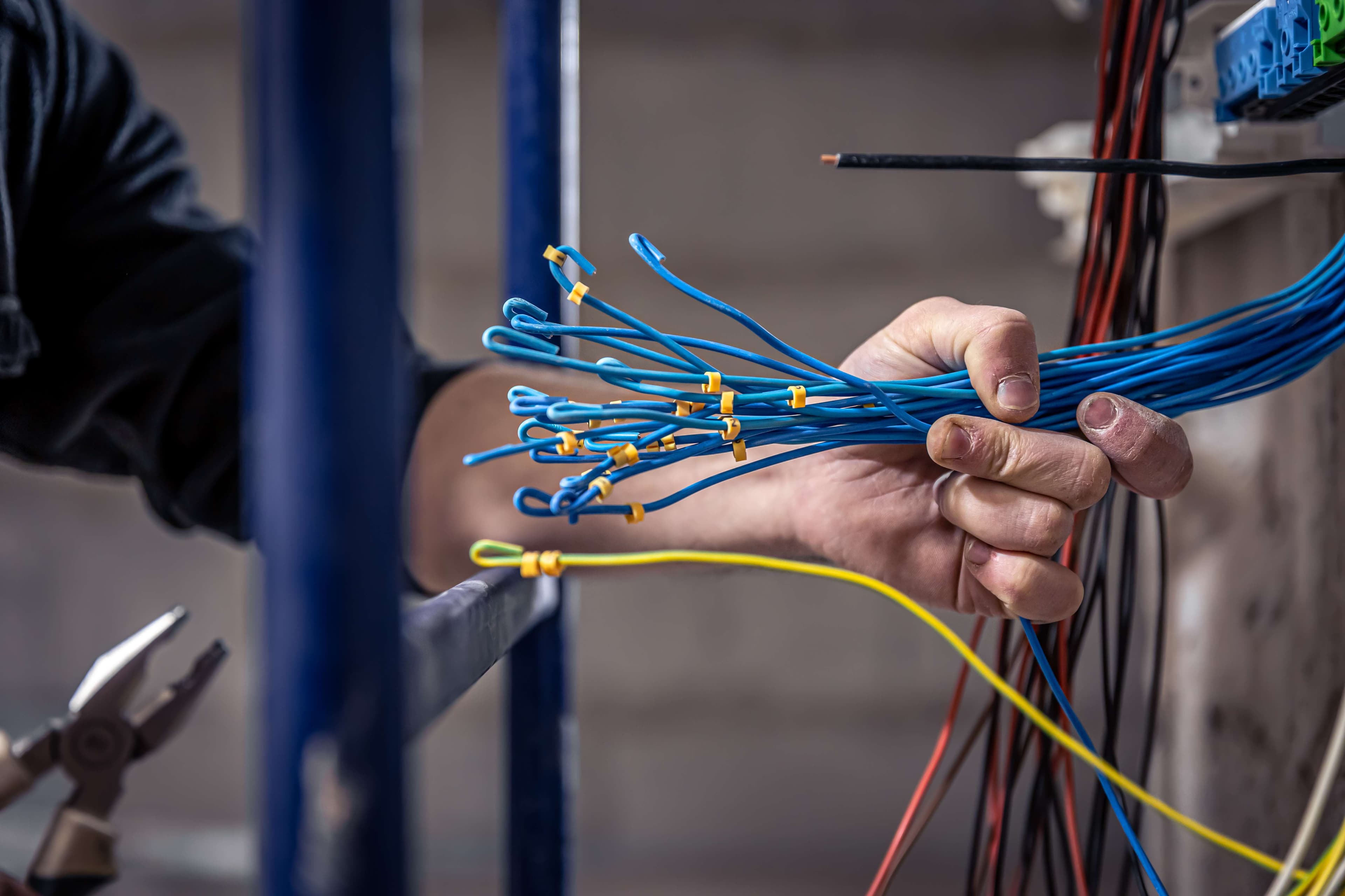 Electrician inspecting home wiring inside a wall panel